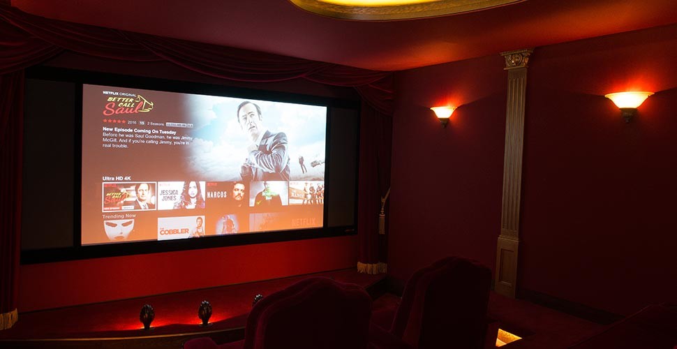 This is an example of a medium sized classic enclosed home cinema in Oxfordshire with red walls, carpet and a projector screen.