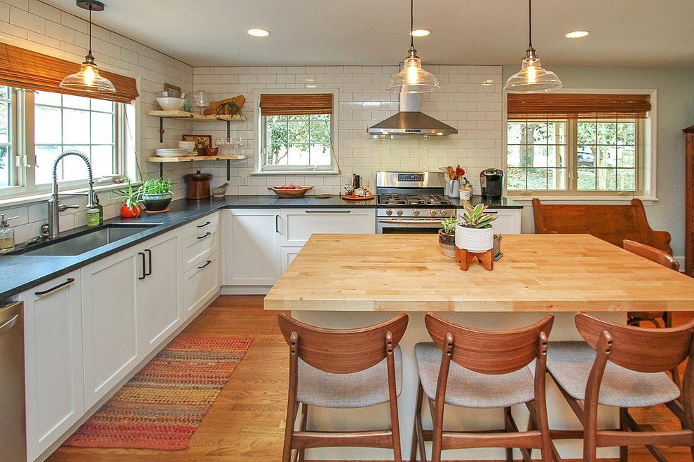 Eat-in kitchen - mid-sized country l-shaped light wood floor and brown floor eat-in kitchen idea in Charlotte with an undermount sink, shaker cabinets, white cabinets, quartz countertops, white backsplash, subway tile backsplash, stainless steel appliances and an island