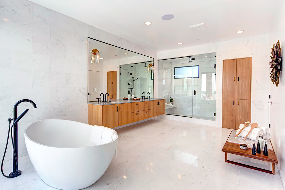This is an example of a large modern master bathroom in Los Angeles with flat-panel cabinets, light wood cabinets, a freestanding tub, white tile, marble, white walls, marble floors, an undermount sink, engineered quartz benchtops, white floor and a hinged shower door.