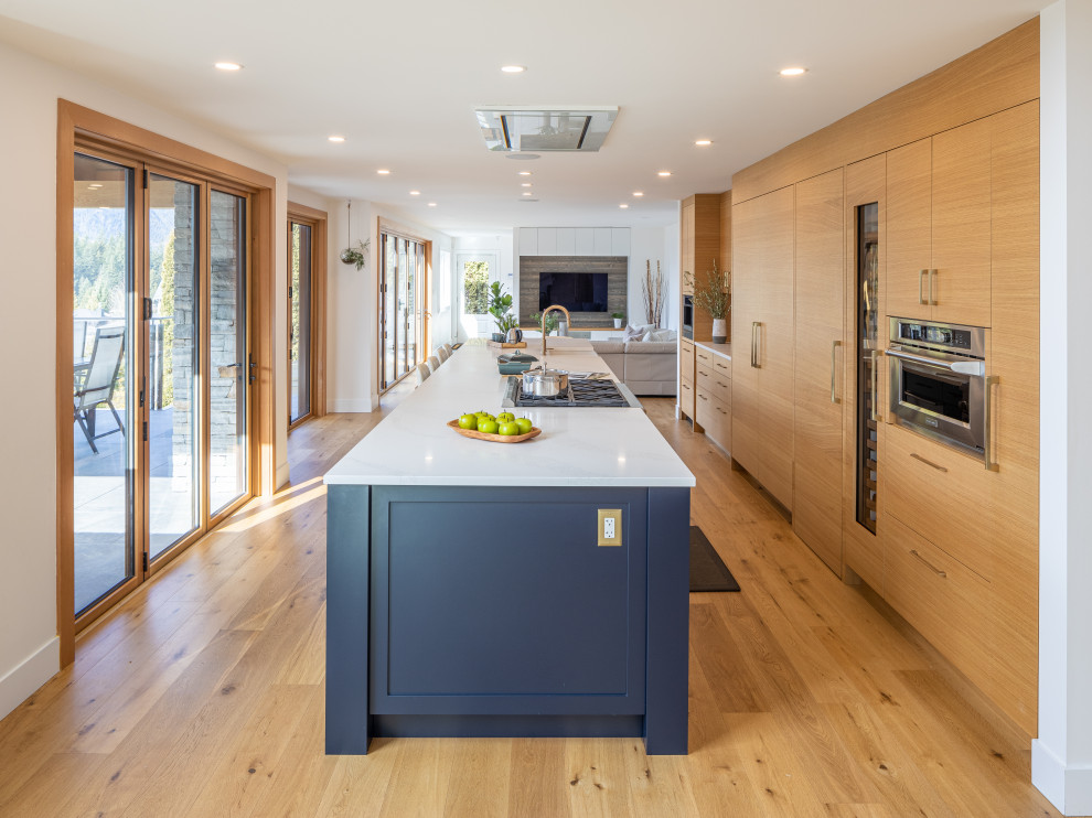 Mid-sized contemporary galley eat-in kitchen in Other with a farmhouse sink, flat-panel cabinets, beige cabinets, quartz benchtops, coloured appliances, medium hardwood floors, with island and white benchtop.