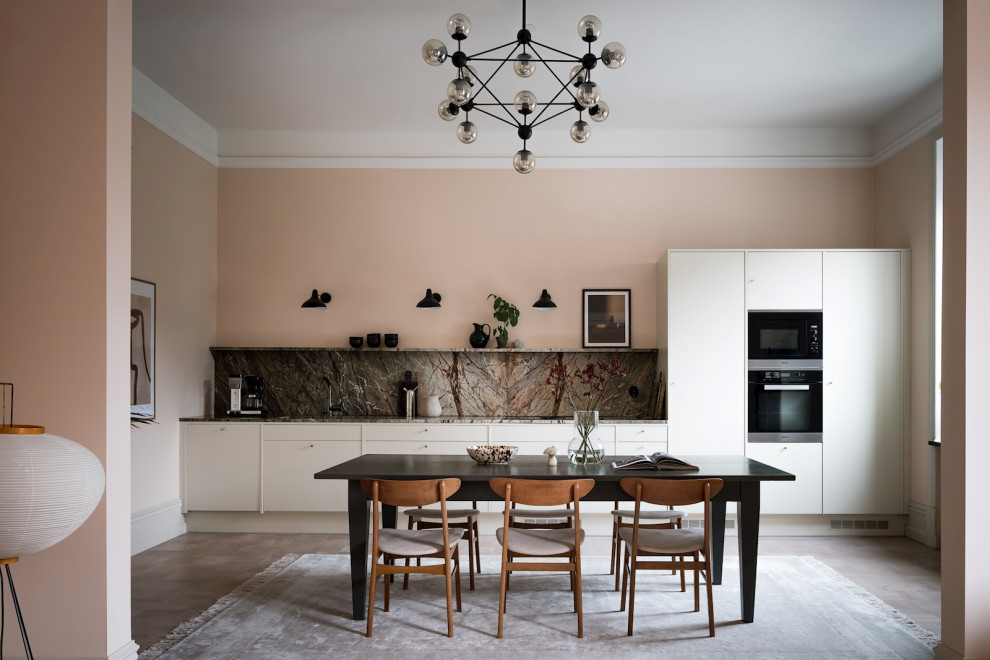 Minimalistisk inredning av ett grå linjärt grått kök och matrum, med släta luckor, vita skåp, grått stänkskydd, stänkskydd i sten, svarta vitvaror, mörkt trägolv och brunt golv