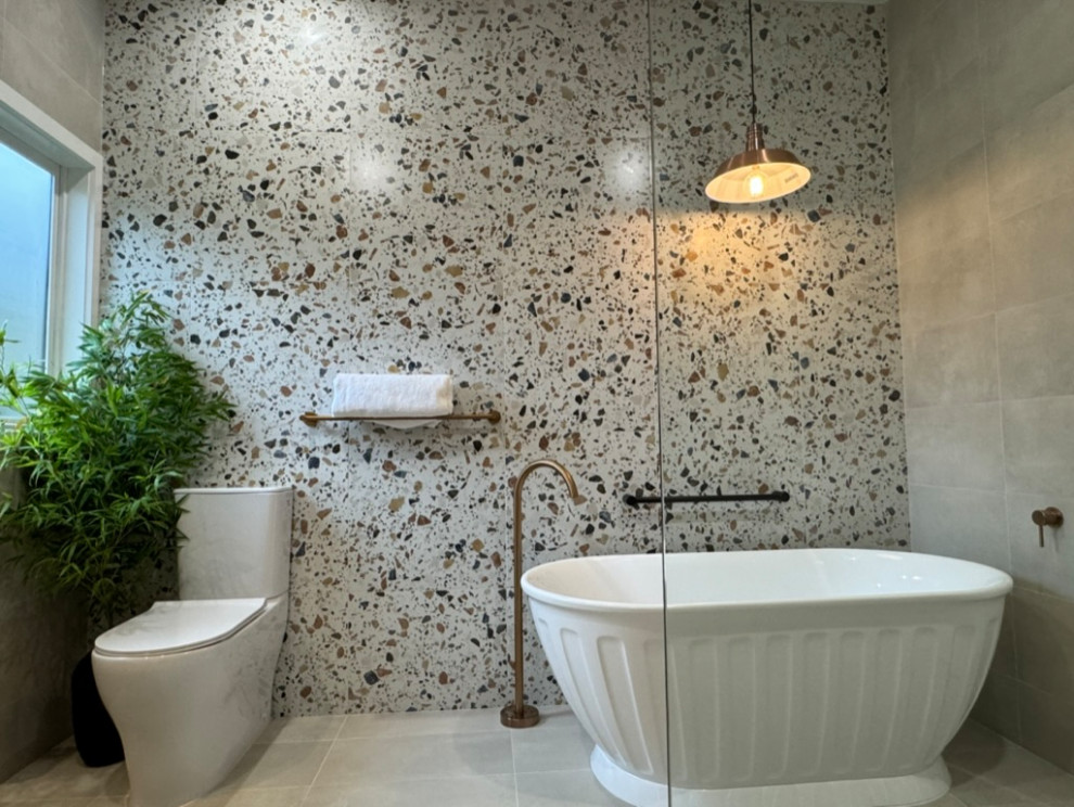 This is an example of a large contemporary ensuite bathroom in Melbourne with a freestanding bath, a built-in shower, a one-piece toilet, multi-coloured tiles, ceramic tiles, ceramic flooring, a vessel sink, wooden worktops, grey floors, an open shower, a single sink, a freestanding vanity unit and a vaulted ceiling.