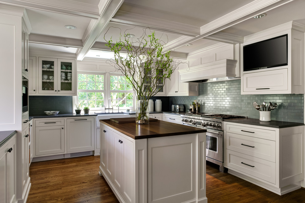 Inspiration for a transitional u-shaped kitchen in Portland with a farmhouse sink, recessed-panel cabinets, white cabinets, green splashback, stainless steel appliances, dark hardwood floors, with island, brown floor and black benchtop.
