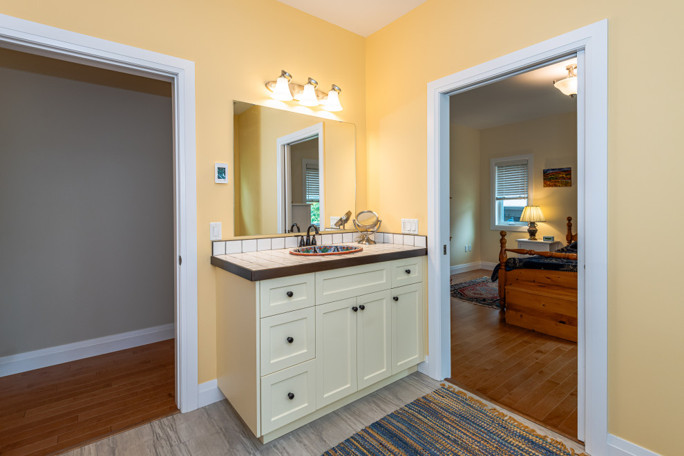 Exemple d'une salle de bain avec un placard avec porte à panneau encastré, des portes de placard jaunes, un mur jaune, un sol en carrelage de céramique, un lavabo posé, un plan de toilette en carrelage, un sol gris, un plan de toilette blanc, meuble simple vasque et meuble-lavabo encastré.