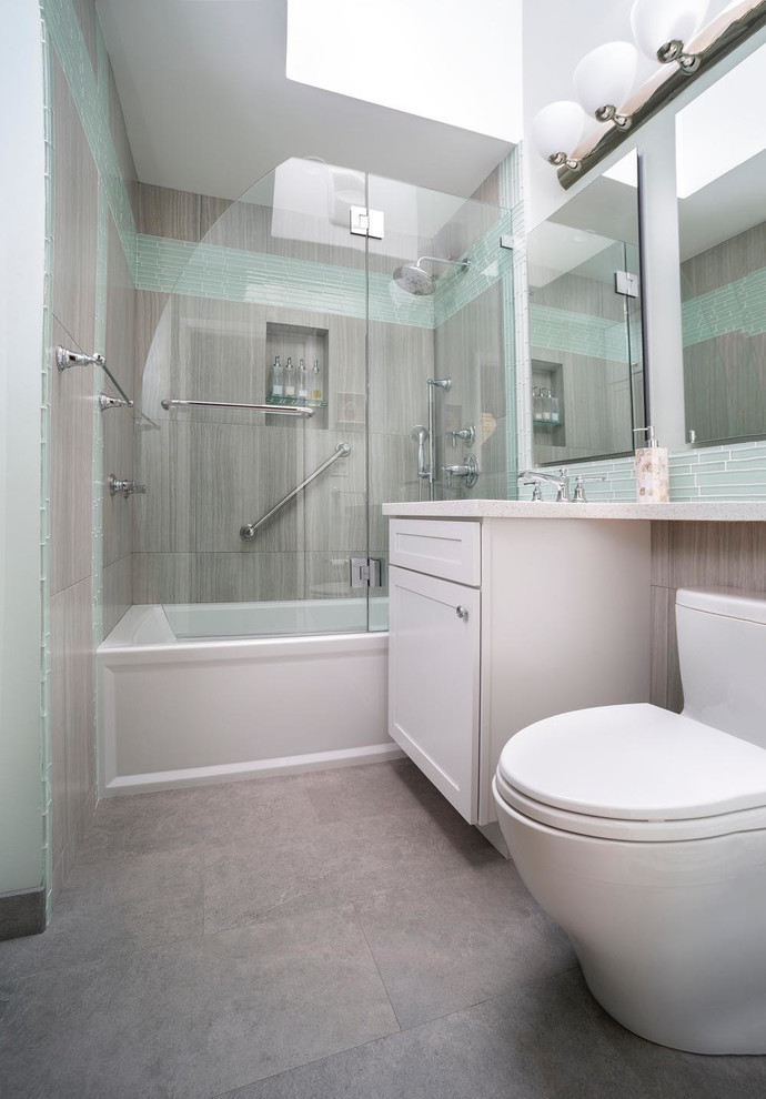 This is an example of a small contemporary 3/4 bathroom in San Francisco with recessed-panel cabinets, white cabinets, an alcove tub, a shower/bathtub combo, a two-piece toilet, glass tile, grey walls, ceramic floors, blue tile, an undermount sink, engineered quartz benchtops, grey floor and a hinged shower door.