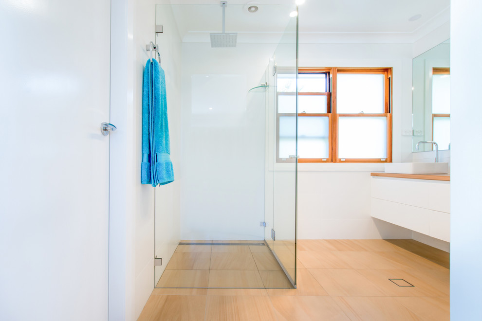 Beach style bathroom in Sydney with a corner shower, white tile, subway tile, white walls, light hardwood floors, wood benchtops, brown floor and a hinged shower door.
