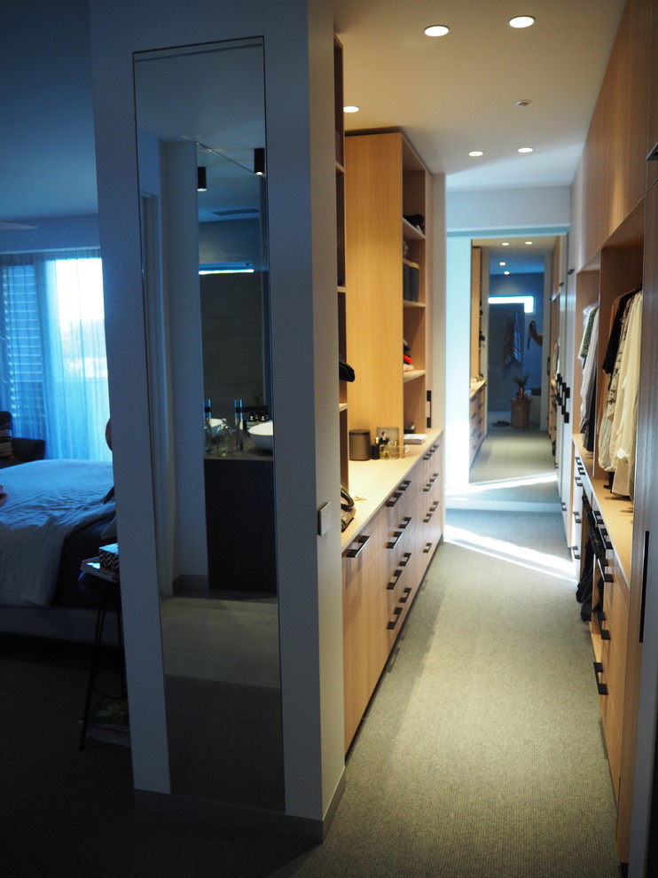 Photo of a mid-sized contemporary gender-neutral walk-in wardrobe in Melbourne with light wood cabinets and carpet.