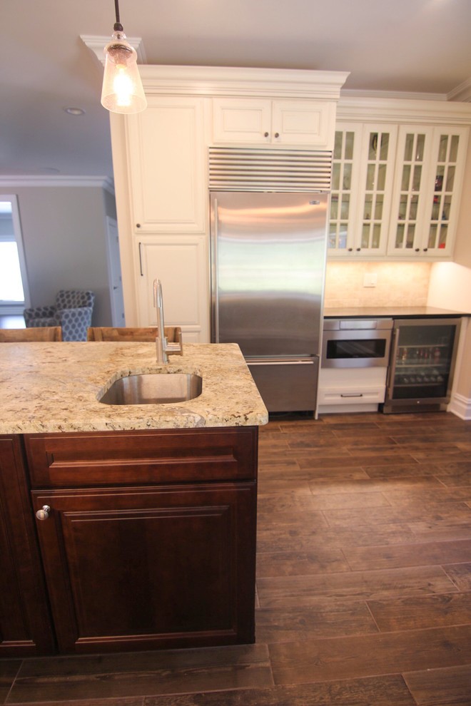 Inspiration for a mid-sized rustic l-shaped dark wood floor and brown floor eat-in kitchen remodel in New York with an undermount sink, raised-panel cabinets, white cabinets, quartzite countertops, beige backsplash, stainless steel appliances, an island and beige countertops