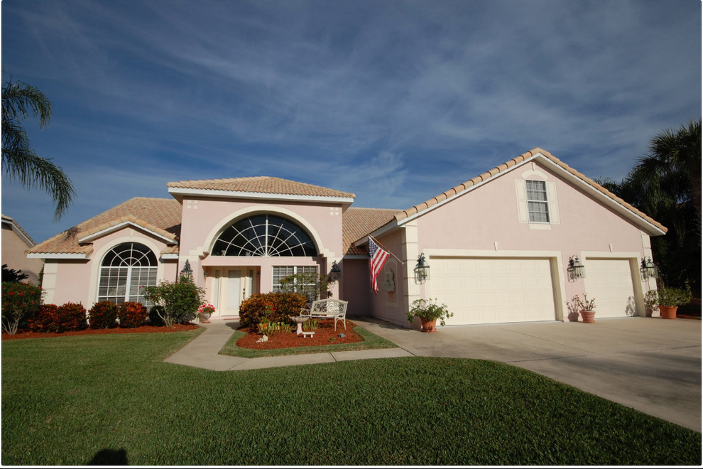 Mid-sized traditional one-storey stucco pink house exterior in Orlando with a hip roof and a tile roof.
