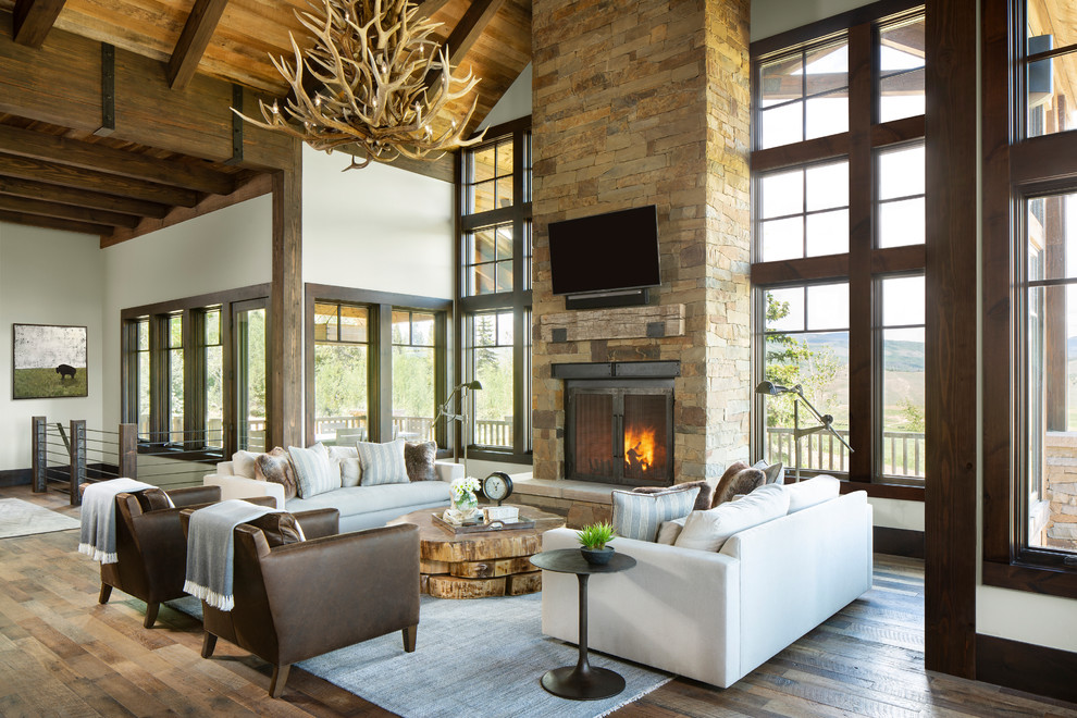 Design ideas for a country open concept family room in Denver with white walls, medium hardwood floors, a standard fireplace, a stone fireplace surround and a wall-mounted tv.