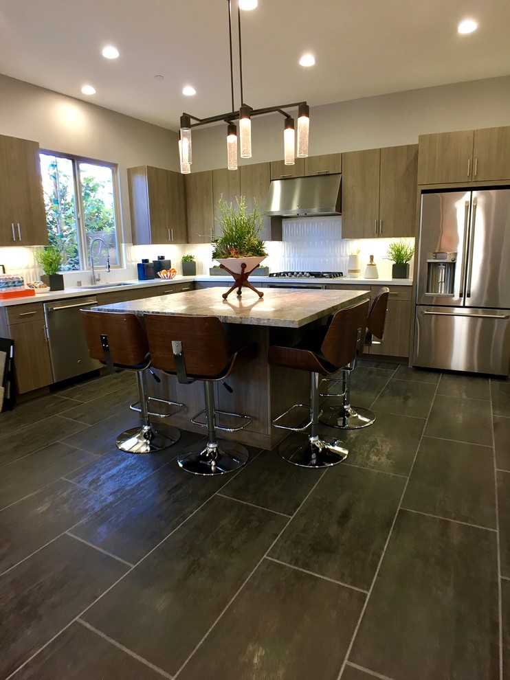 Photo of a mid-sized eclectic l-shaped eat-in kitchen in Los Angeles with an undermount sink, flat-panel cabinets, medium wood cabinets, granite benchtops, white splashback, subway tile splashback, stainless steel appliances, porcelain floors and with island.