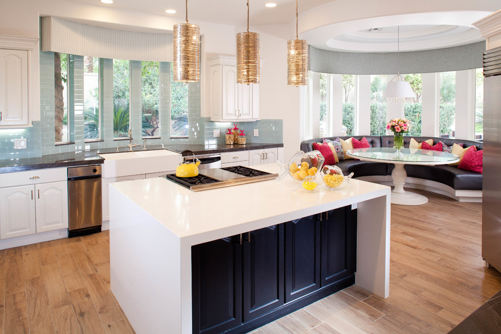 Photo of a contemporary eat-in kitchen in Las Vegas with a farmhouse sink, raised-panel cabinets, white cabinets, blue splashback, light hardwood floors and with island.