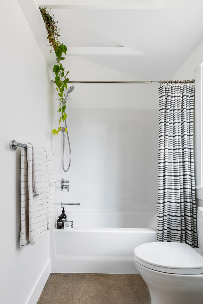 Design ideas for a beach style bathroom in Portland with flat-panel cabinets, white cabinets, an alcove tub, a shower/bathtub combo, a two-piece toilet, white walls, concrete floors, a vessel sink, wood benchtops, grey floor and a shower curtain.