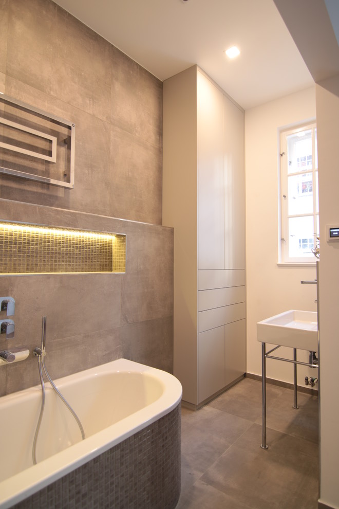 This is an example of a mid-sized contemporary 3/4 bathroom in Munich with a freestanding tub, beige tile, cement tile, white walls, cement tiles, a console sink and beige floor.