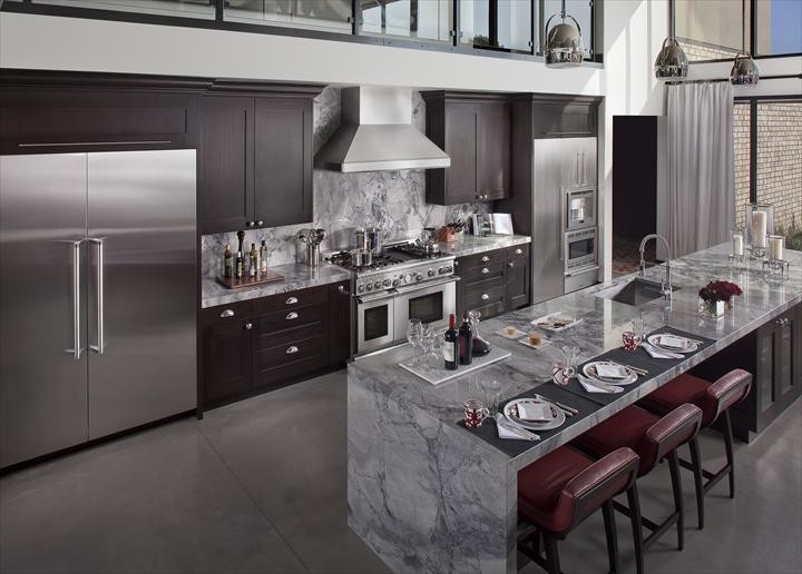 Photo of a large country l-shaped eat-in kitchen in Toronto with an undermount sink, shaker cabinets, dark wood cabinets, marble benchtops, grey splashback, stone slab splashback, stainless steel appliances, concrete floors and with island.