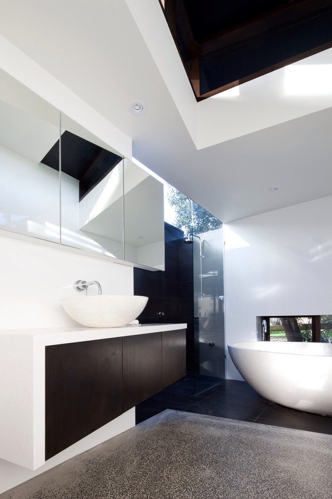 Modern bathroom in Melbourne with a vessel sink, flat-panel cabinets, dark wood cabinets, a freestanding tub, an alcove shower and white benchtops.
