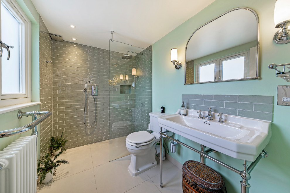 Photo of a transitional bathroom in London with a curbless shower, a two-piece toilet, gray tile, green walls, a console sink, grey floor, an open shower, a niche and a single vanity.