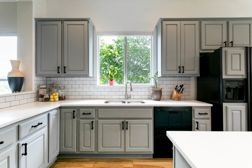 Inspiration for a transitional u-shaped porcelain tile and brown floor eat-in kitchen remodel in Austin with a double-bowl sink, gray cabinets, quartz countertops, white backsplash, ceramic backsplash, black appliances and an island