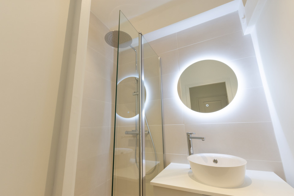 Foto på ett litet funkis en-suite badrum, med vita skåp, en vägghängd toalettstol, beige kakel, keramikplattor, vita väggar, ett nedsänkt handfat och beiget golv