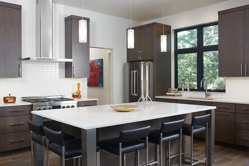 Large contemporary u-shaped open plan kitchen in Grand Rapids with white splashback, stainless steel appliances, with island, an undermount sink, flat-panel cabinets, dark wood cabinets, ceramic splashback, dark hardwood floors, brown floor and white benchtop.