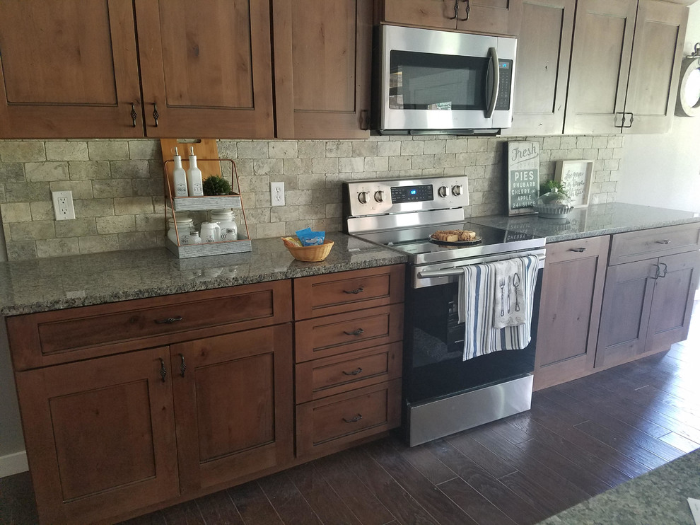 Mid-sized mountain style single-wall dark wood floor and brown floor open concept kitchen photo with an undermount sink, shaker cabinets, dark wood cabinets, granite countertops, beige backsplash, stone tile backsplash, stainless steel appliances and an island