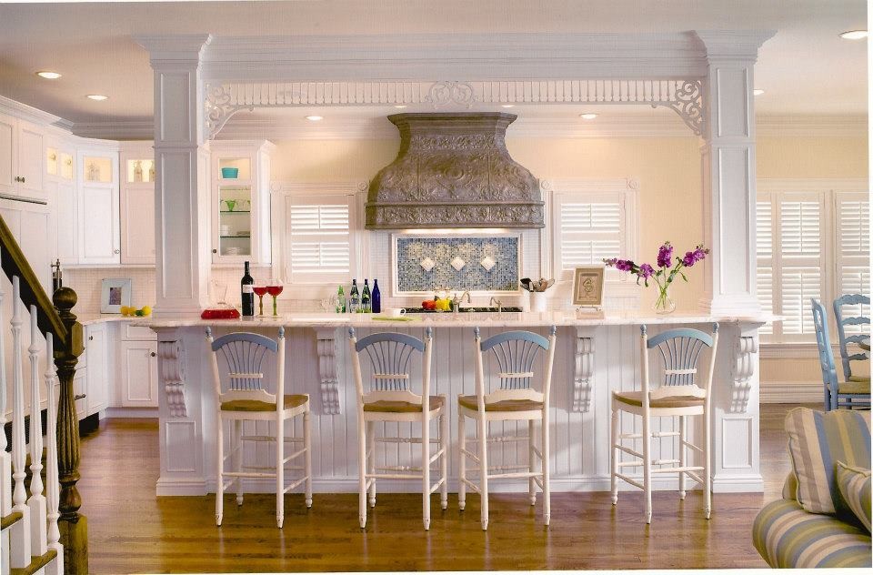 Photo of a mid-sized beach style l-shaped eat-in kitchen in New York with a farmhouse sink, flat-panel cabinets, white cabinets, marble benchtops, white splashback, panelled appliances and medium hardwood floors.