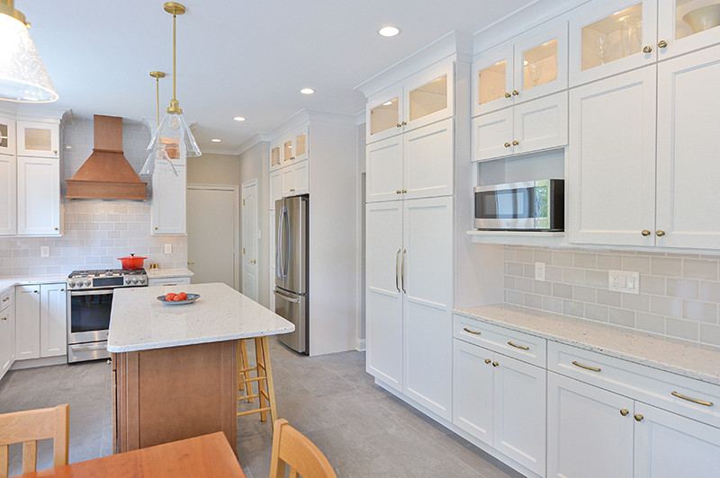 Inspiration for a large transitional l-shaped open plan kitchen in Philadelphia with shaker cabinets, white cabinets, subway tile splashback, stainless steel appliances, with island, beige floor and white benchtop.