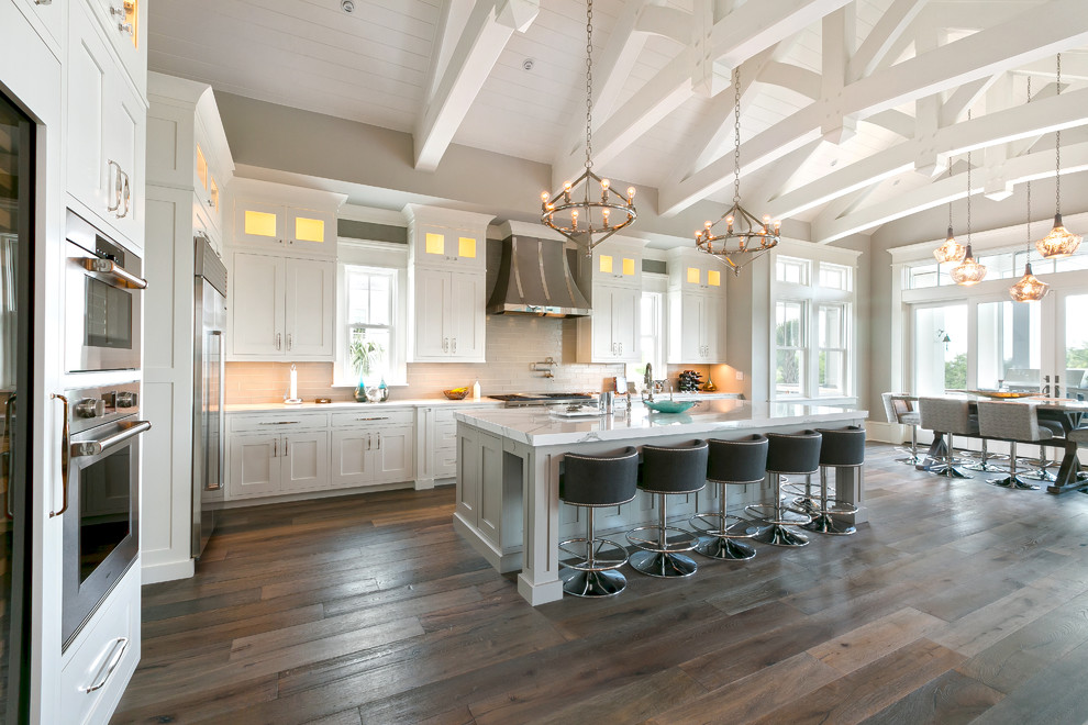Inspiration for a transitional l-shaped medium tone wood floor and brown floor eat-in kitchen remodel in Charleston with shaker cabinets, white cabinets, beige backsplash, stainless steel appliances and an island