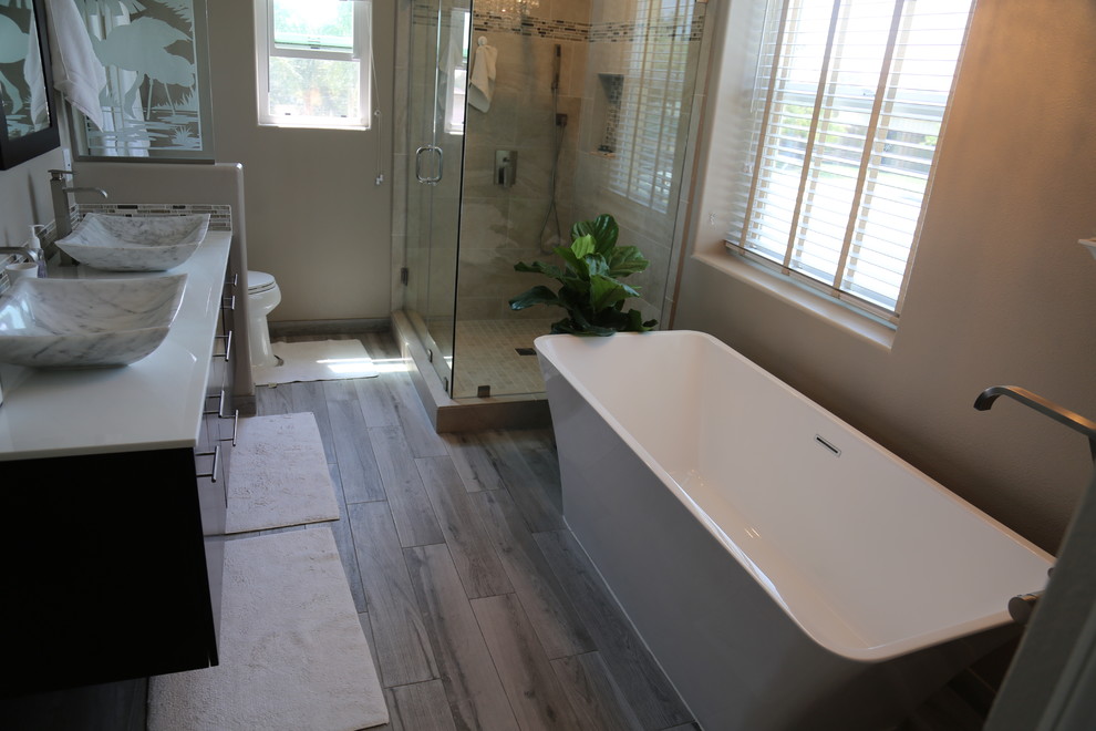Photo of a contemporary master bathroom in Los Angeles with flat-panel cabinets, black cabinets, a freestanding tub, a corner shower, beige tile, brown walls and a vessel sink.