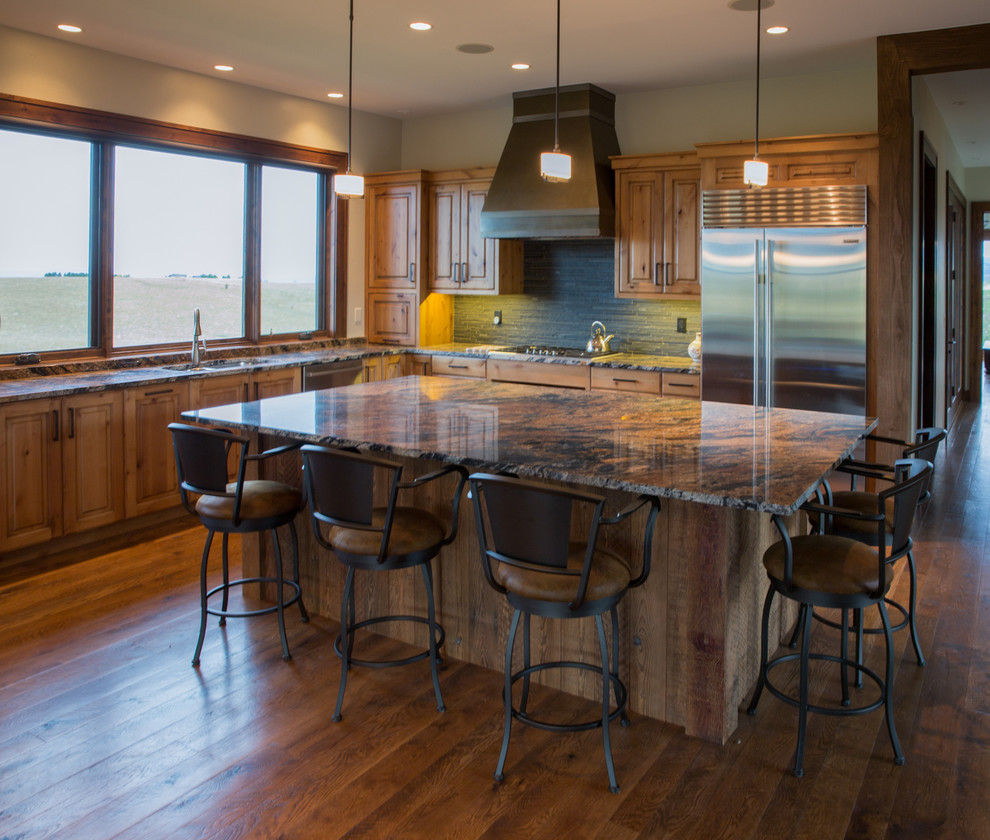 Inspiration for a transitional l-shaped light wood floor eat-in kitchen remodel with an island, a drop-in sink, flat-panel cabinets, medium tone wood cabinets, granite countertops, gray backsplash, stone tile backsplash and stainless steel appliances