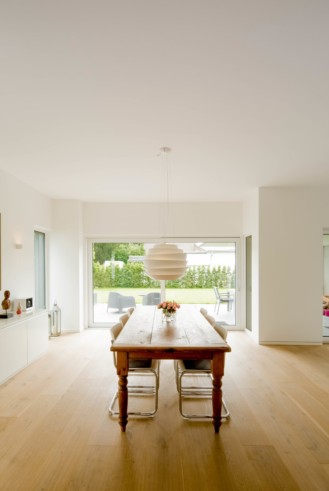 Large contemporary open plan dining in Dusseldorf with white walls and light hardwood floors.
