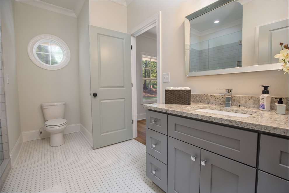 Large country master bathroom in Atlanta with recessed-panel cabinets, grey cabinets, an alcove shower, a two-piece toilet, gray tile, subway tile, beige walls, marble floors, an undermount sink, granite benchtops, grey floor, a hinged shower door and multi-coloured benchtops.