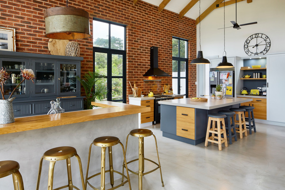 Open concept kitchen - mid-sized transitional galley concrete floor open concept kitchen idea with quartz countertops, an island, flat-panel cabinets, light wood cabinets and stainless steel appliances