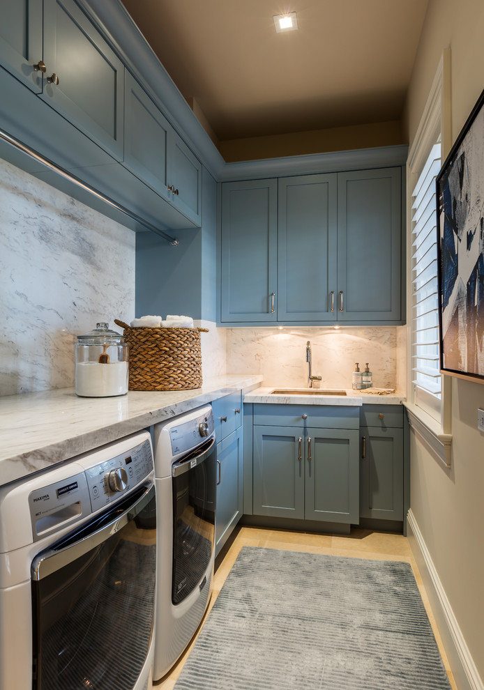 Design ideas for a transitional l-shaped dedicated laundry room in Miami with an undermount sink, shaker cabinets, blue cabinets, beige walls, light hardwood floors, a side-by-side washer and dryer and white benchtop.