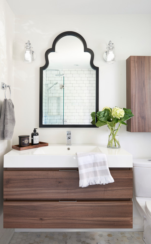 Inspiration for a small transitional kids bathroom in Toronto with flat-panel cabinets, medium wood cabinets, a drop-in tub, a shower/bathtub combo, a two-piece toilet, multi-coloured tile, mosaic tile, grey walls, marble floors, a trough sink and engineered quartz benchtops.