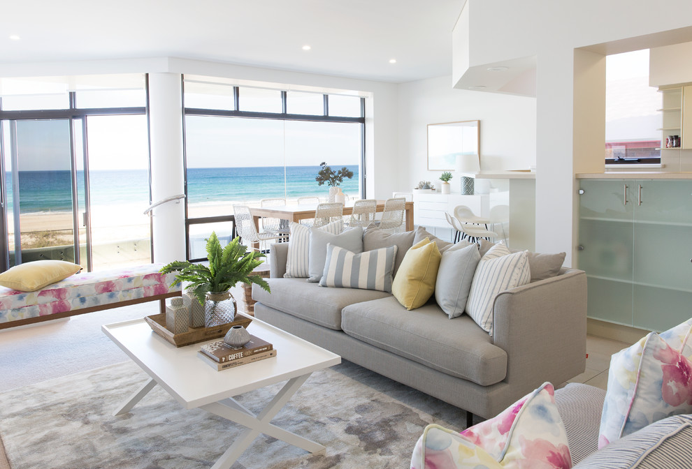 This is an example of a large beach style formal open concept living room in Gold Coast - Tweed with white walls, carpet, a freestanding tv and beige floor.