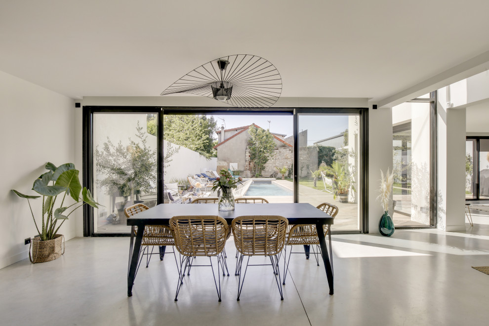 Idées déco pour une salle à manger ouverte sur le salon contemporaine avec un mur blanc, sol en béton ciré et un sol gris.
