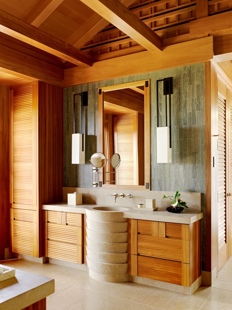 Design ideas for a tropical bathroom in Hawaii with louvered cabinets, medium wood cabinets, brown tile, gray tile, brown walls, a pedestal sink and beige floor.