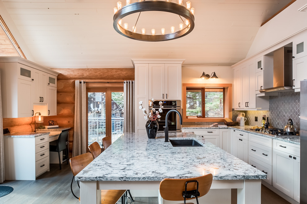 This is an example of a country l-shaped kitchen in Other with a double-bowl sink, shaker cabinets, white cabinets, grey splashback, stainless steel appliances, dark hardwood floors and with island.