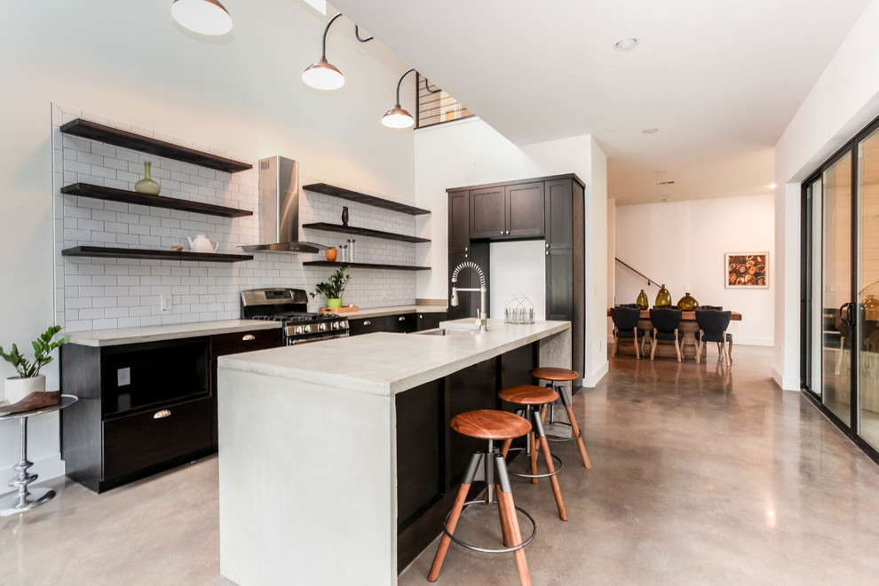 This is an example of a mid-sized transitional eat-in kitchen in Austin with subway tile splashback, open cabinets, dark wood cabinets, concrete benchtops, white splashback, concrete floors and with island.