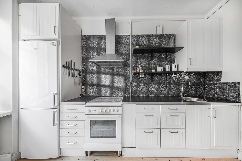 This is an example of a small scandinavian single-wall kitchen in Stockholm with white cabinets and stainless steel benchtops.