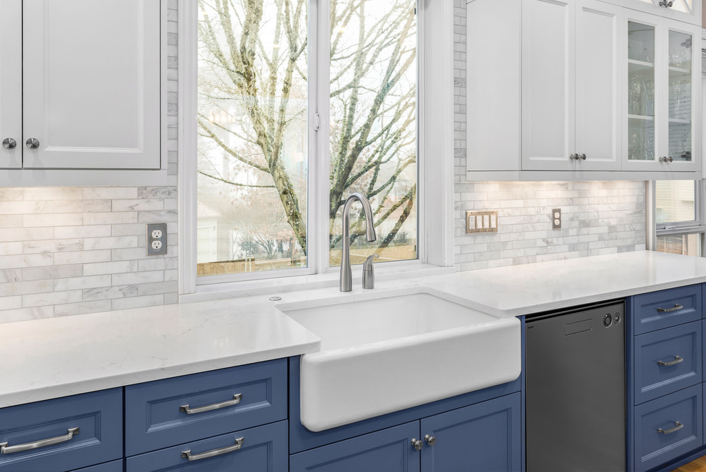 Inspiration for a mid-sized traditional l-shaped eat-in kitchen in Portland with a farmhouse sink, recessed-panel cabinets, blue cabinets, quartz benchtops, white splashback, marble splashback, stainless steel appliances, porcelain floors and with island.