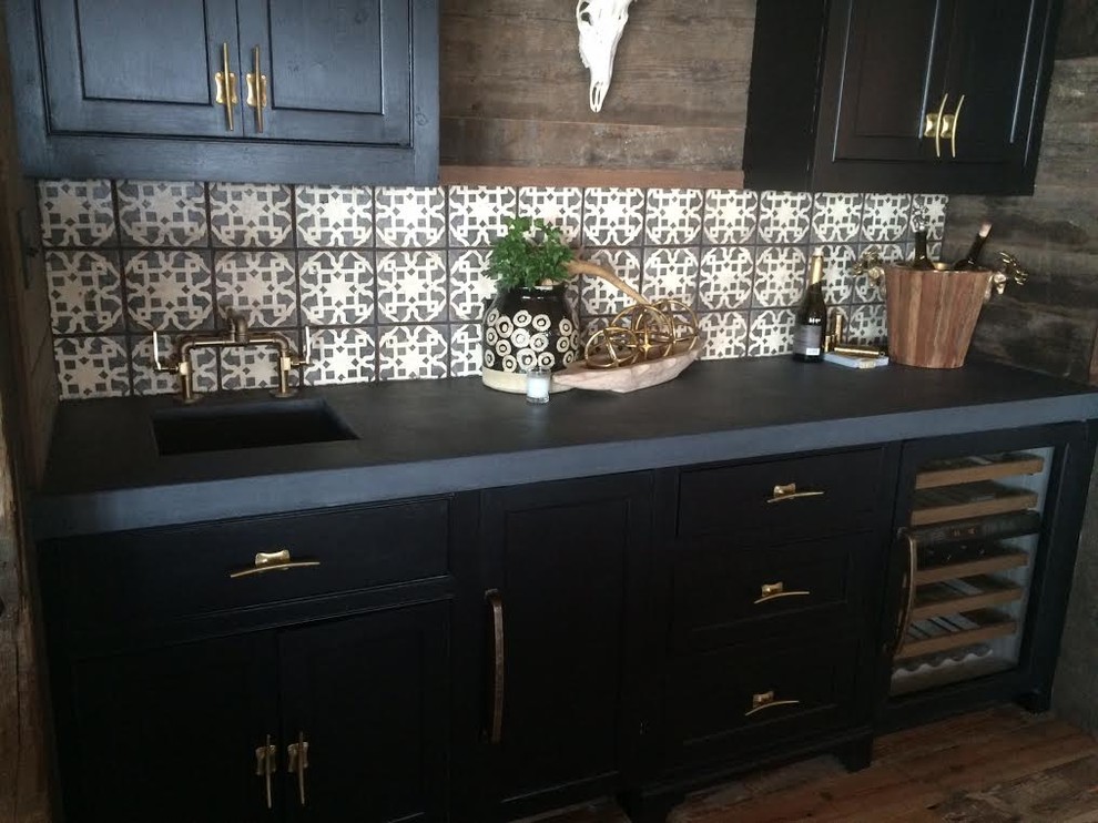 Inspiration for a mid-sized eclectic single-wall wet bar in New Orleans with recessed-panel cabinets, black cabinets, concrete benchtops, grey splashback, terra-cotta splashback and medium hardwood floors.