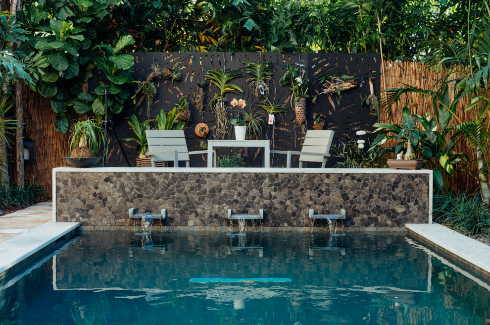 Diseño de piscina alargada de estilo zen pequeña rectangular en patio trasero con paisajismo de piscina y adoquines de piedra natural