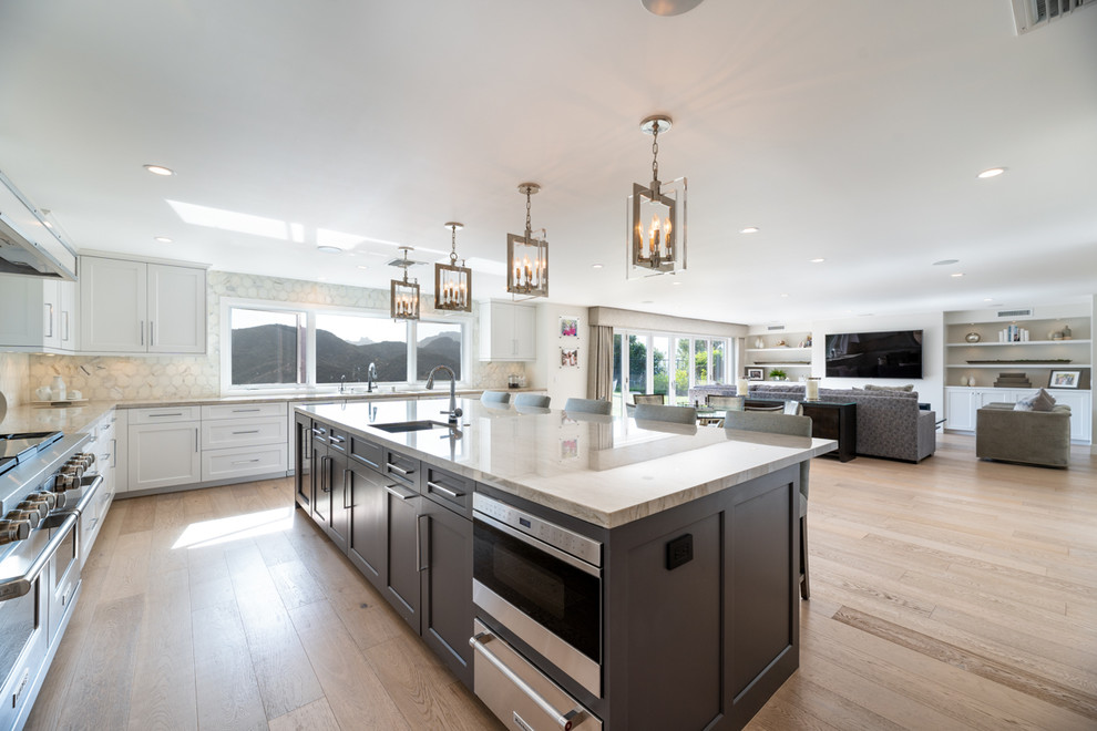 Open concept kitchen - huge transitional u-shaped light wood floor open concept kitchen idea in Los Angeles with an undermount sink, shaker cabinets, quartz countertops, stainless steel appliances and an island
