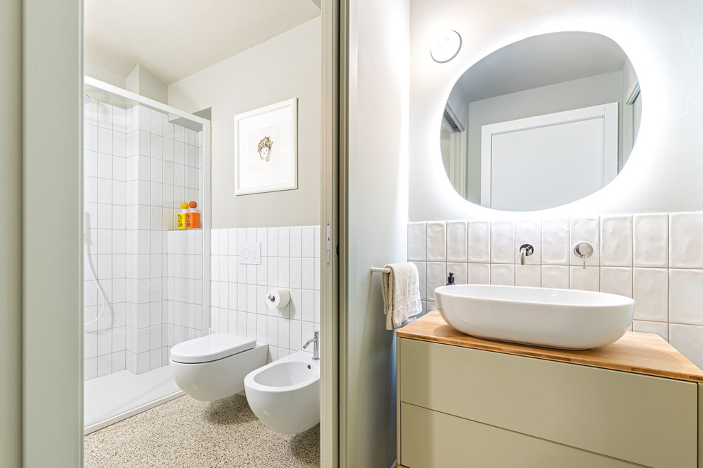 Inspiration for a small midcentury 3/4 bathroom in Turin with flat-panel cabinets, grey cabinets, a wall-mount toilet, white tile, ceramic tile, grey walls, terrazzo floors, a vessel sink, wood benchtops, grey floor, a sliding shower screen, a niche, a single vanity and a freestanding vanity.