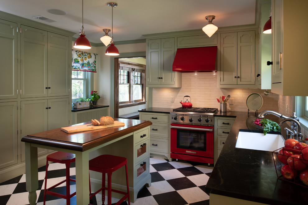 Design ideas for a mid-sized eclectic separate kitchen in Minneapolis with an undermount sink, flat-panel cabinets, green cabinets, soapstone benchtops, beige splashback, ceramic splashback, coloured appliances, linoleum floors, multi-coloured floor and black benchtop.