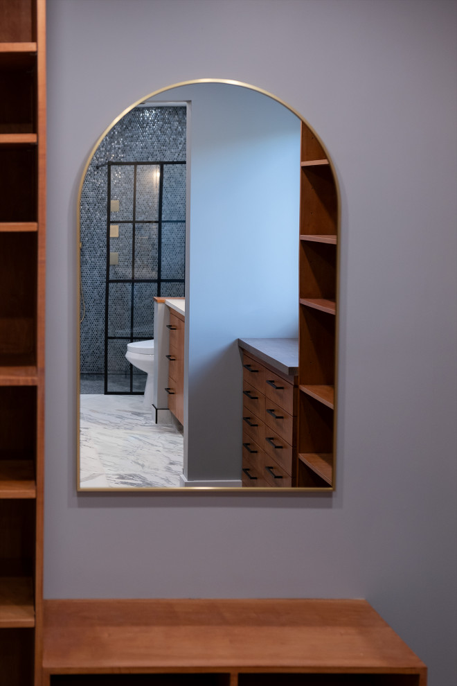 This is an example of a contemporary gender neutral walk-in wardrobe in Ottawa with flat-panel cabinets, medium wood cabinets, laminate floors and brown floors.