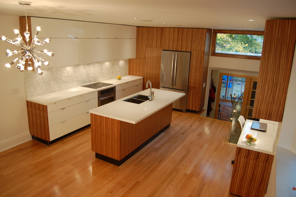 This is an example of a mid-sized modern eat-in kitchen in Toronto with an undermount sink, flat-panel cabinets, medium wood cabinets, quartz benchtops, white splashback, stone slab splashback, stainless steel appliances, light hardwood floors and with island.