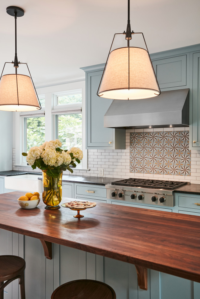 Large transitional porcelain tile and beige floor eat-in kitchen photo in New York with a farmhouse sink, beaded inset cabinets, blue cabinets, wood countertops, multicolored backsplash, ceramic backsplash, stainless steel appliances, an island and brown countertops